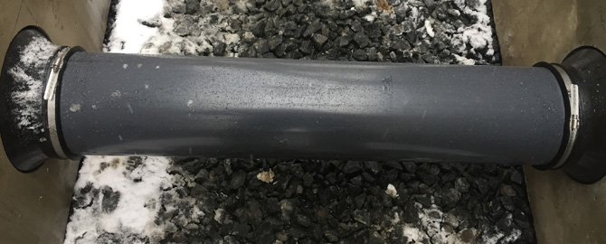Black pipe connecting two concrete boxes