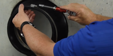 Mans hand in blue shirt tightening a wrench