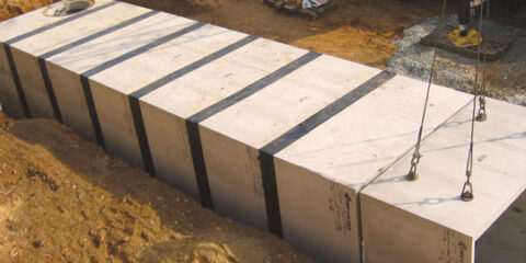 Box culvert being lowered down into a ditch with other concrete boxes